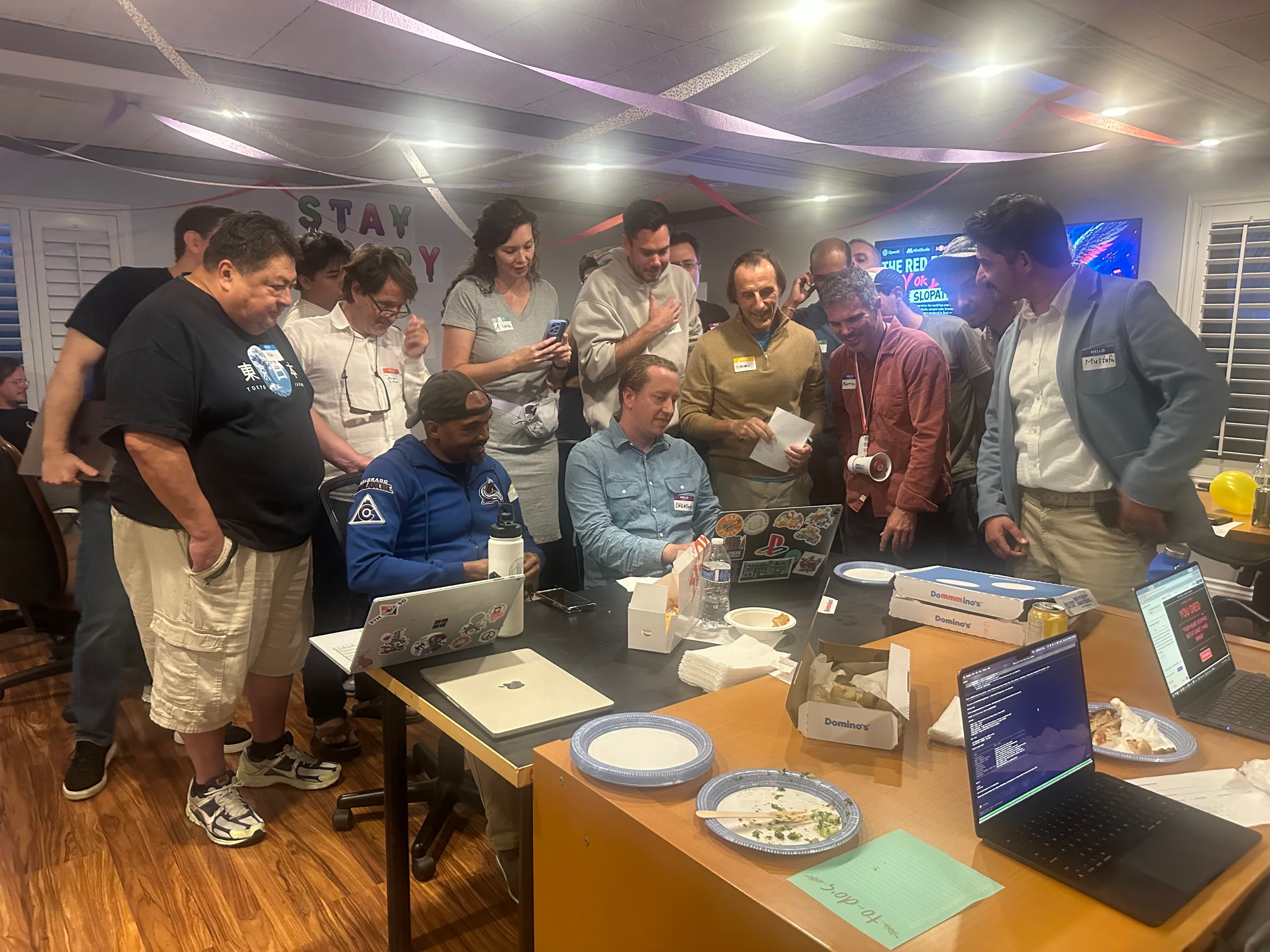 Slopathon participants crowded around laptops watching a live demo